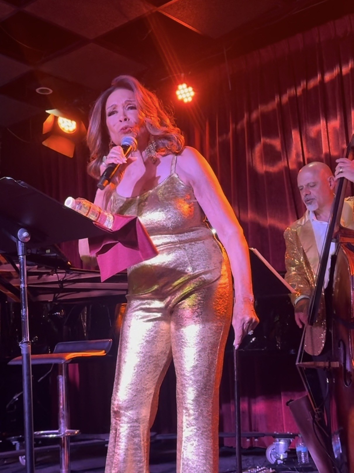 Freda Payne in a gold lame halter and flared trousers, leaning into the microphone under red stage light at Catalina Jazz Club